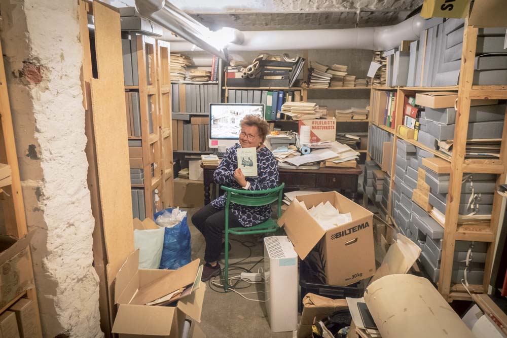 Christina Snellman i SFV:s källararkiv bland dammiga mappar.