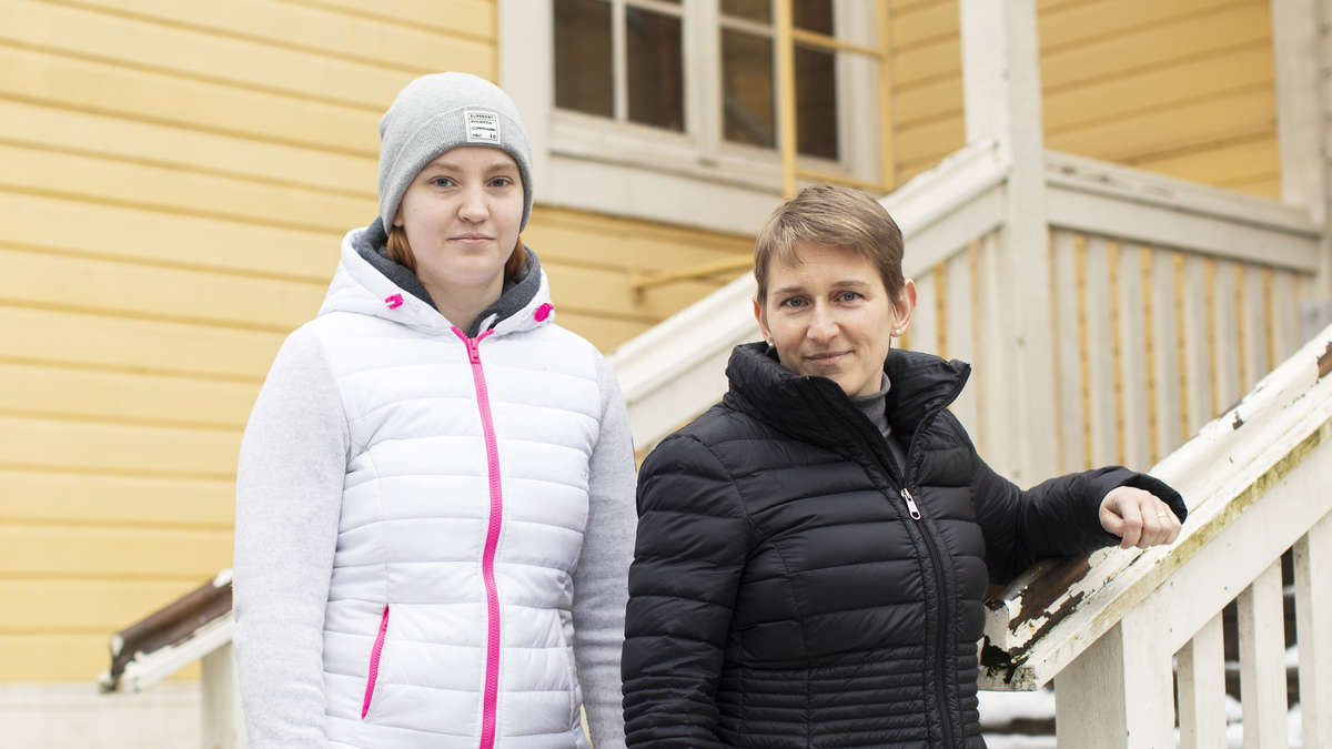 Vivian Ljungqvist och Katja Salojärvi står vinterklädda utanför ett gult trähus.