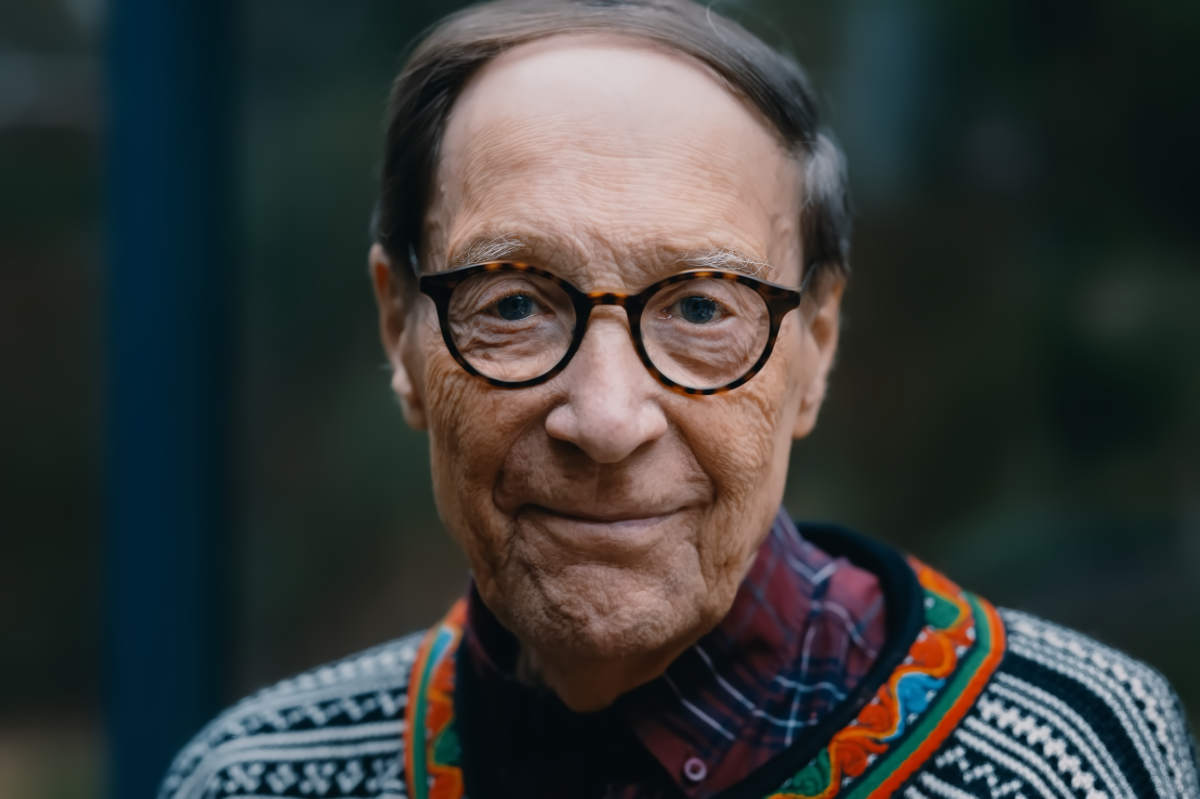 Pär Stenbäkc är ute, och tittar rakt i kameran i en närbild. Han har en färggrann norsk ylletröja på sig, undertill en rutig flanellskjorta.
