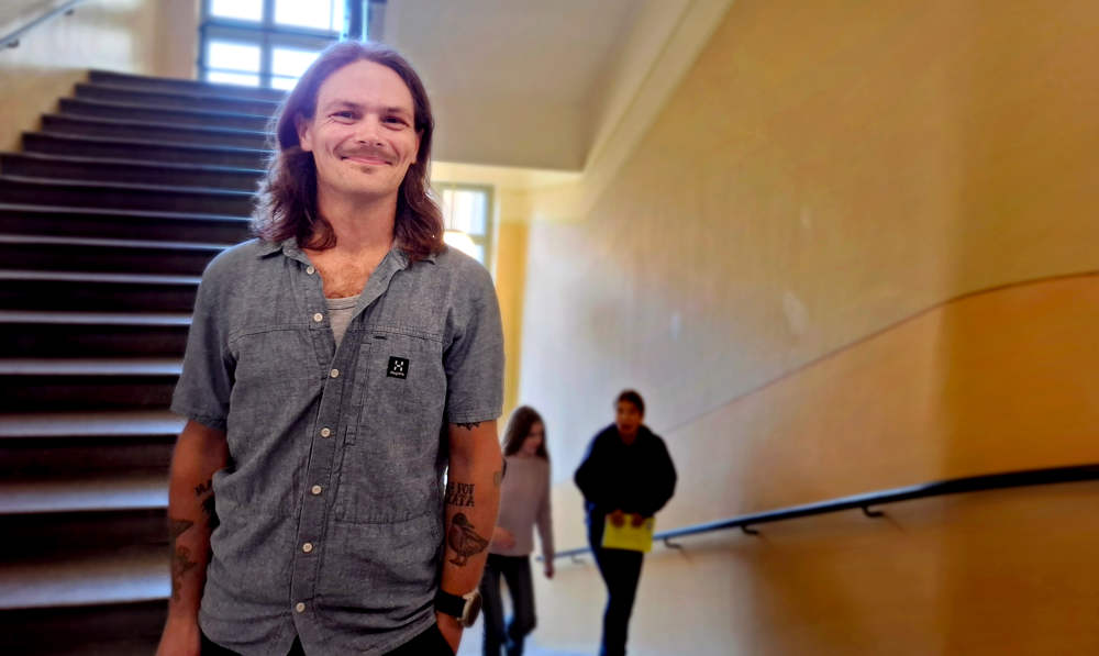 Tomas Luoto i Norsen trappuppgång. Han har skjortärmarna uppvikta, så man ser hans tatuerade armar