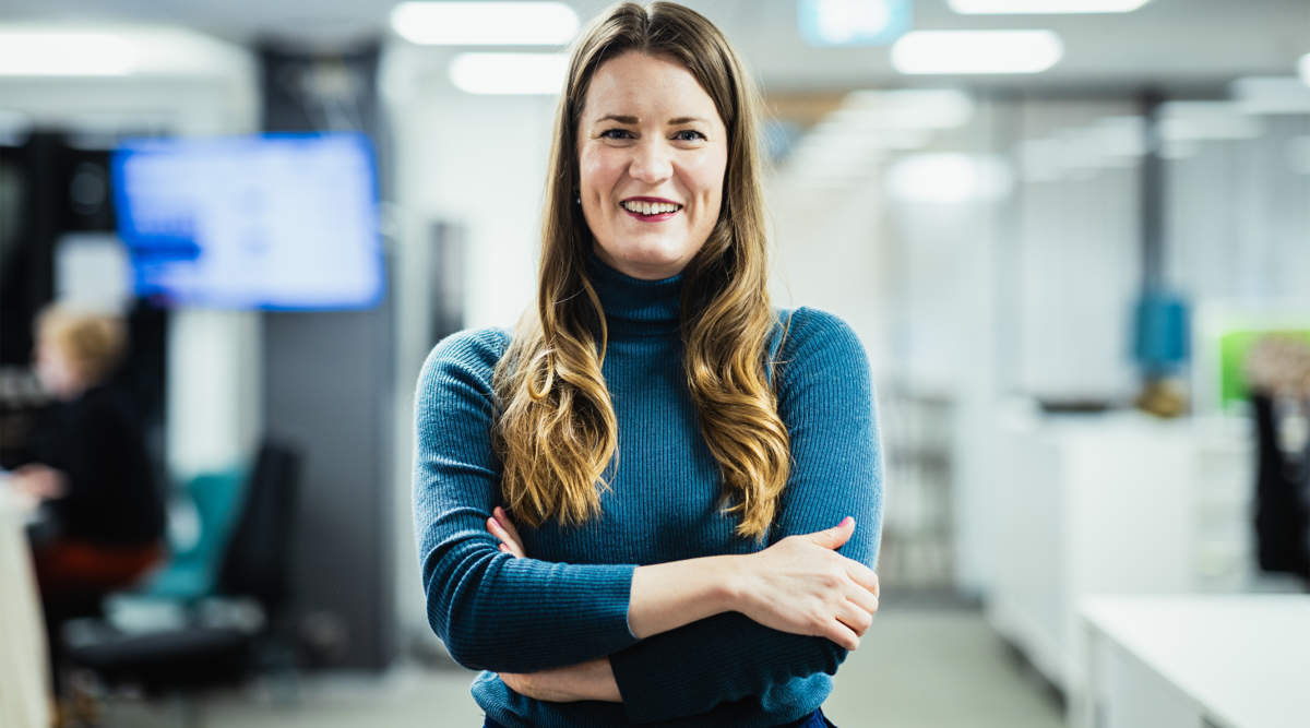 Marianne Sundholm står med händerna korslagda i Hbls redaktionsvåning, som dock är blöurrad så man ser inte så mycket.