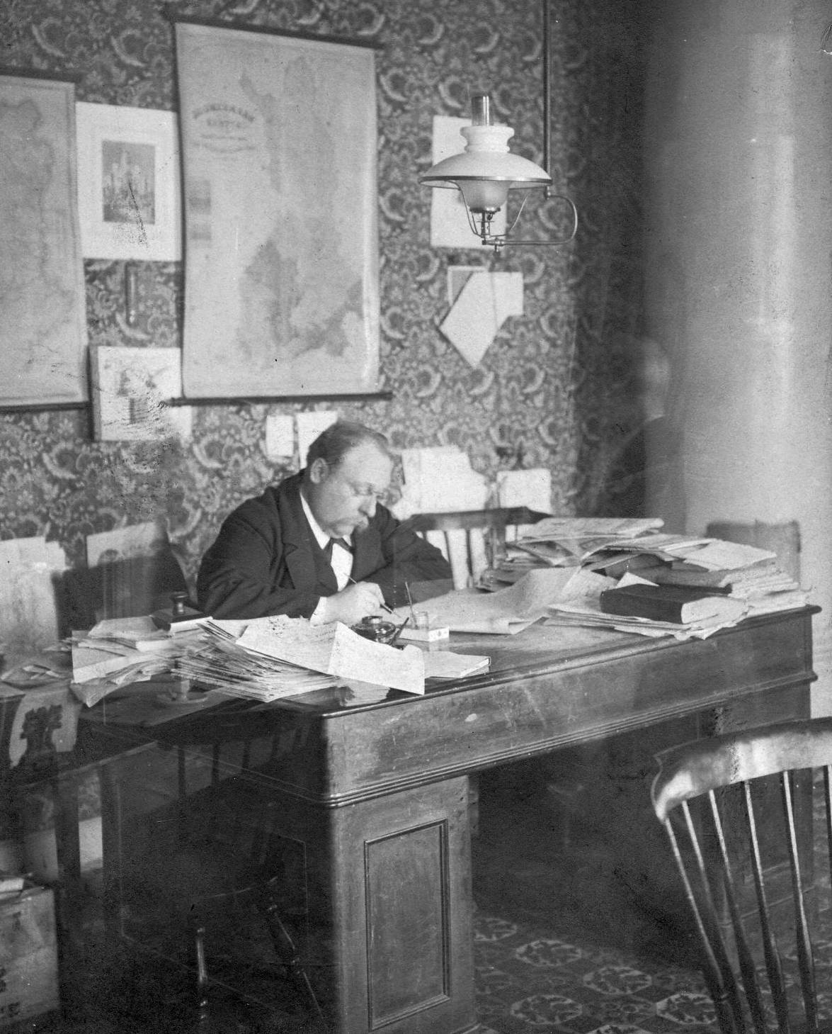 J. F. Hagfors vid sitt arbetsbord, belamrat med papper.