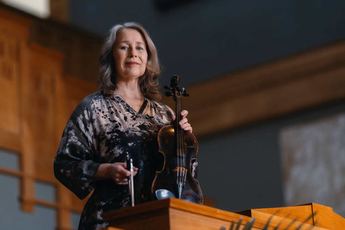 Marianne Maans står i en trappuppgång med en fiol i handen.